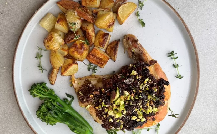 A chicken supreme on a plate coated in a pistachio crust served with potatoes and broccoli | Herd Fed Poultry