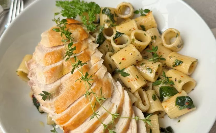 A sliced Herb Fed Chicken on a plate served with pasta and fresh herbs | Herb Fed Poultry
