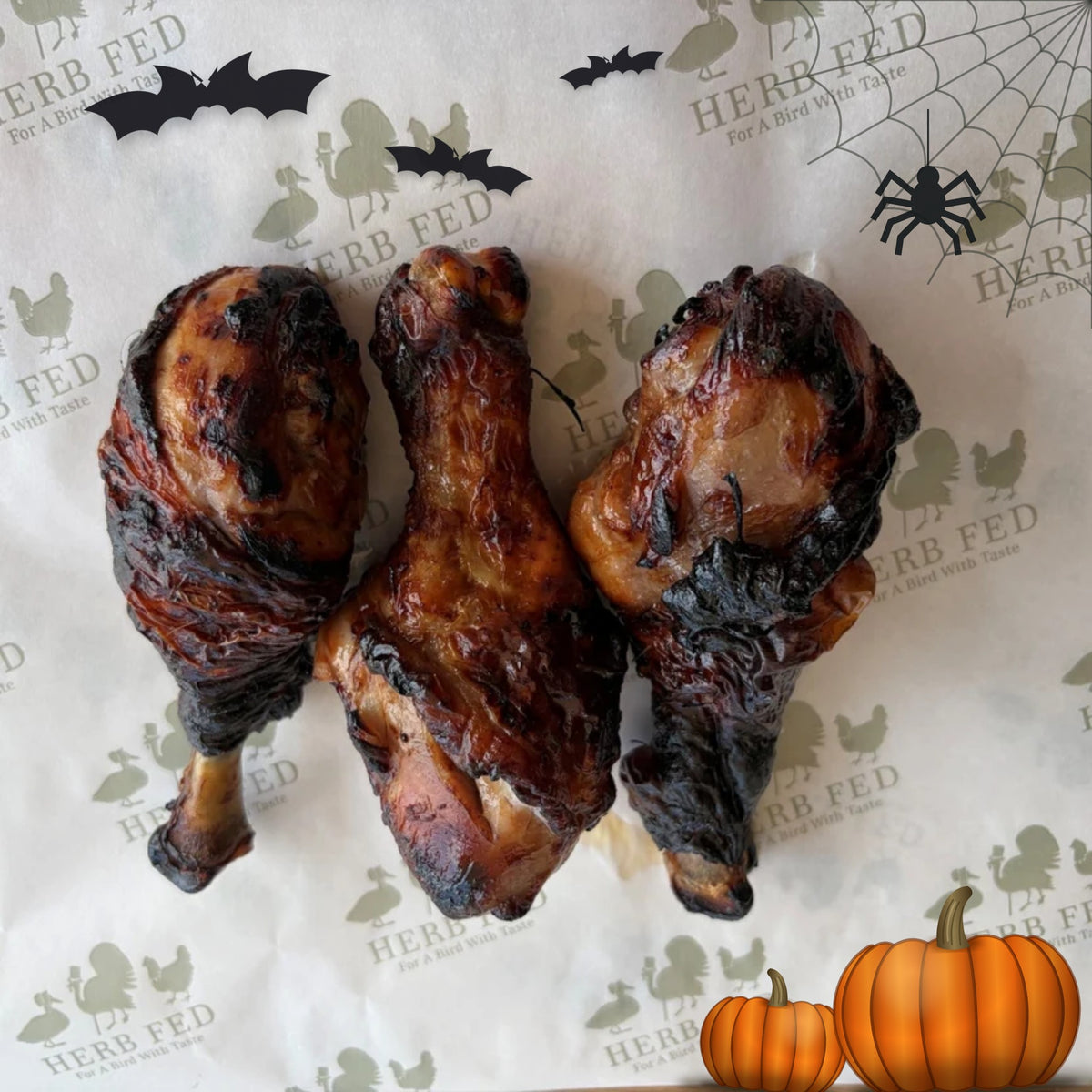 Herb Fed Drumsticks marinated in a pomegranate molasses sauce laid on a white board on a wooden table. Ideal for a Halloween feast.