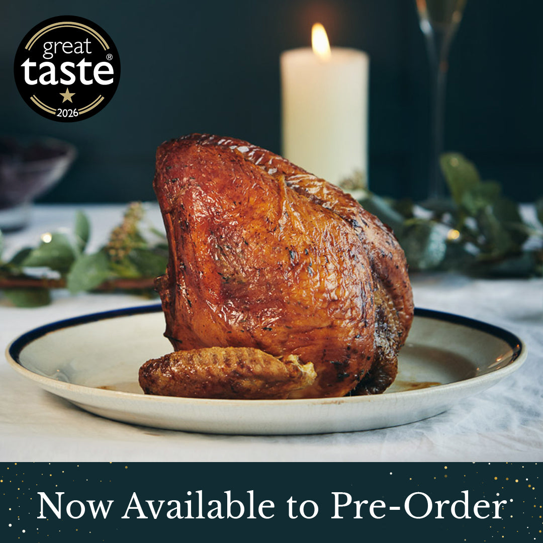 A roasted Herb Fed Thanksgiving bronze turkey crown on a white plate with a dark rim, set on a table with a lit candle, glass, and greenery in the background. A '1 star great taste 2026' badge appears in the top-left, and a banner at the bottom reads 'Now Available to Pre-Order'.
