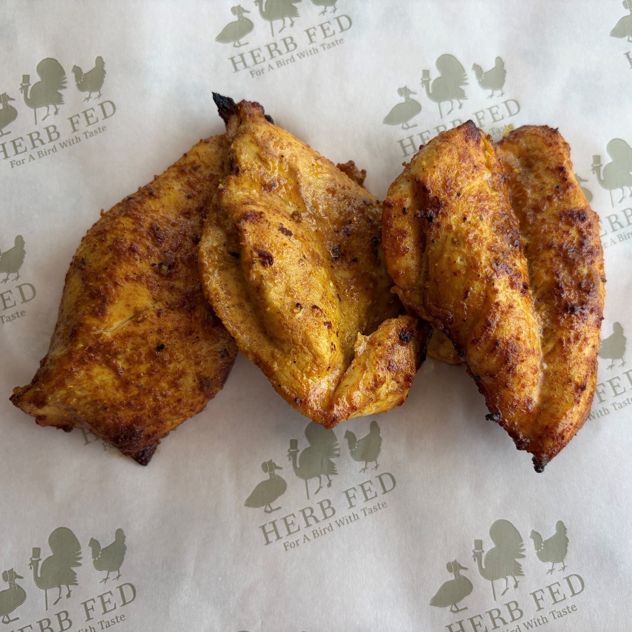 Three pieces of golden-brown fried plantain or sweet potato wedges arranged on white paper printed with the Herb Fed logo.