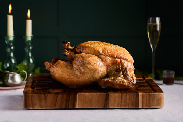 A cooked rooster on a wooden board | Herb Fed Poultry